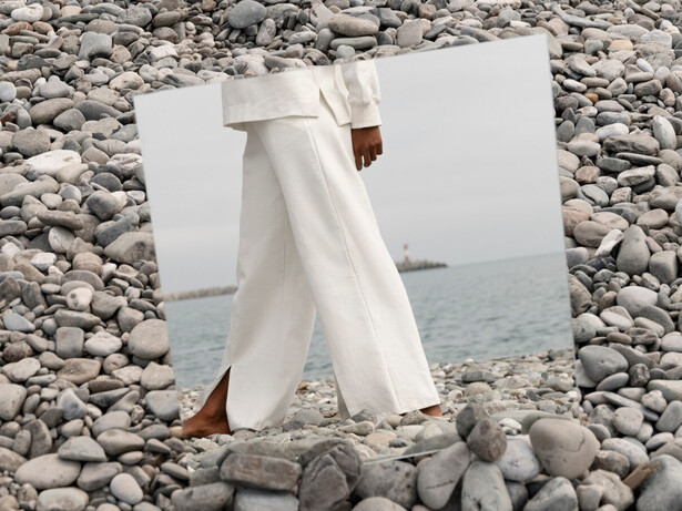 Barefoot on the rocks, a model steps into herself grounded in reflection and free to feel