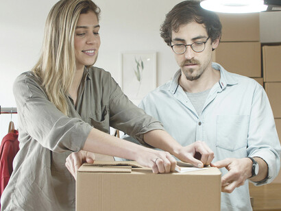 A man and a woman pack orders together at a table in a small business warehouse