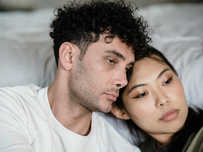 An unhappy couple sitting together, looking worried