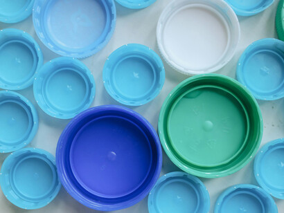 Blue and green plastic bottle caps of varied colors