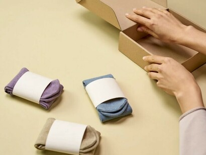 A person assembling a cardboard box for eco-friendly clothing made from plant-based fibers, promoting sustainable fashion