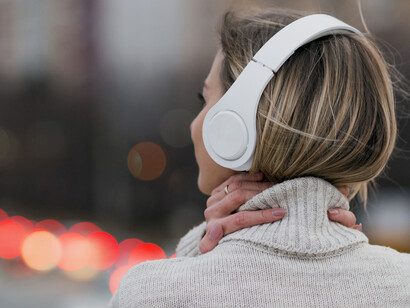 Woman on a rooftop, wearing headphones, captured from behind