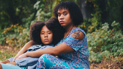 A woman and her daughter sitting on grass