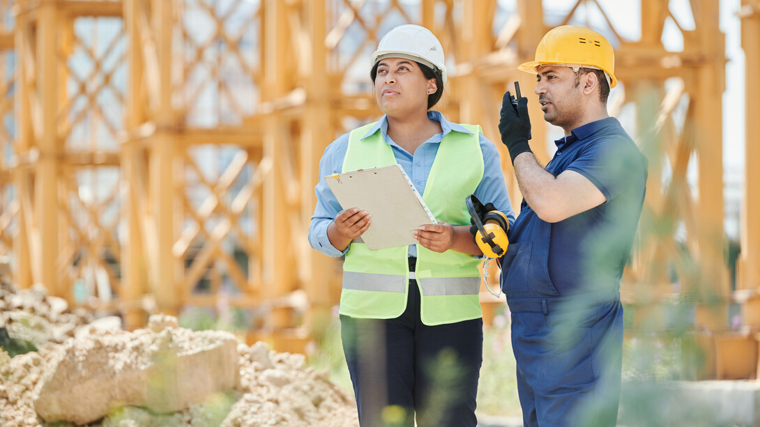 Engenheira e mestre de obra analisam projeto em área verde