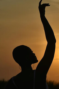 As the sun dips below the horizon in Accra, located in the picturesque Greater Accra Region of Ghana, the warm hues of the sunset illuminate the scene, casting a captivating glow on a woman immersed in the tranquil beauty of the moment