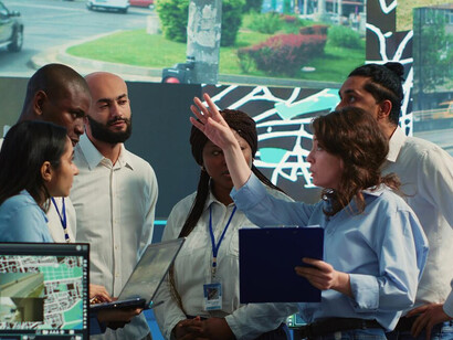 A diverse team of professionals engages in discussions and hands-on work, utilizing generative AI, satellite imagery, and advanced machine learning techniques to innovate in geospatial technology and digital transformation
