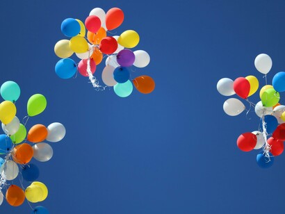 Trois lots de ballons s'envolant dans le ciel, représentant liberté et émancipation