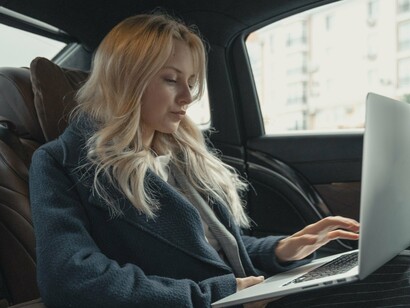 Woman busy working on a laptop in the car