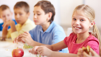 Smiling girl enjoying grapes as part of a healthy school lunch