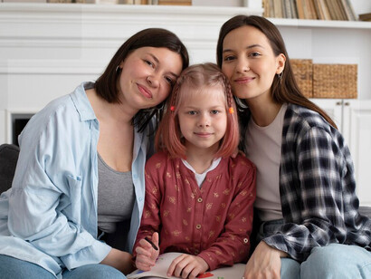 Two moms enjoying a cozy afternoon at home with their daughter, showcasing the warmth and unity of same-sex families