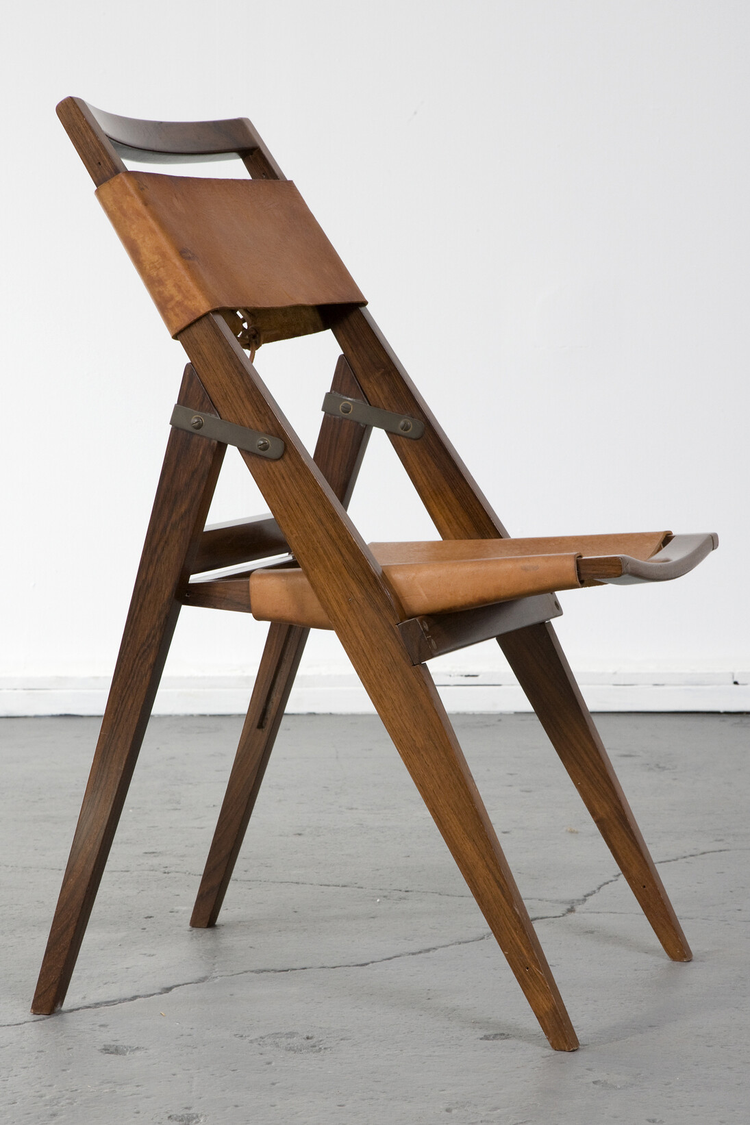 Folding chair with jacaranda frame and leather seat. Designed by Lina Bo Bardi for Studio de Arte Palma, Brazil, circa 1950. (seat height: 16.5") 17.75" L x 16.75" W x 32.25" H / 45.1cm L x 42.5cm W x 81.9cm H. Photo: Joe Kramm/R & Company.