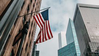 An American flag waves on the side of a brick building