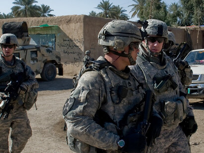 Soldiers walking through a destroyed city in Diyala, Iraq, armed and wearing tactical gear in an urban war zone