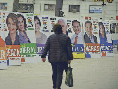  A woman walks a street full of electoral propaganda in Santiago, Chile