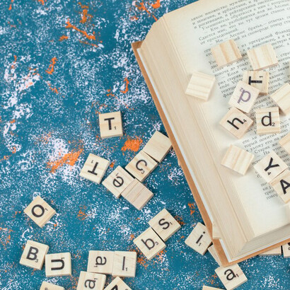 Wooden letters printed placed between the pages of a book, symbolizing the origins of language