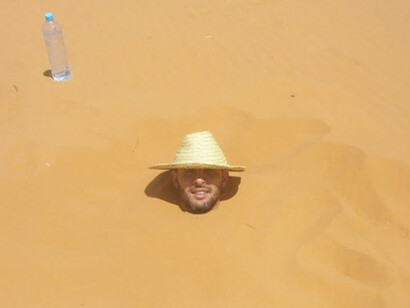The person is buried in the sand leaving the head free
