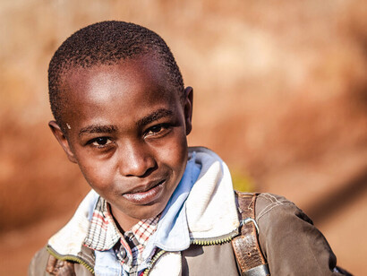 With a slight smile on his face, this young boy embodies hope and resilience as he makes his way to school, a testament to the power of education in the fight against poverty