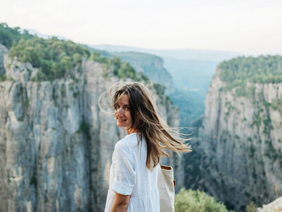 A smiling woman at the top of a canyon, embracing a peaceful mountain travel experience