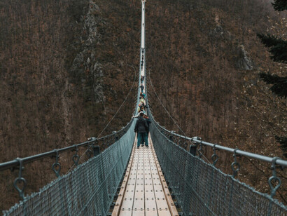 Le pont suspendu symbolise la continuité du monde naturel : chaque pas relie deux rives sans rupture, rappelant que tout changement authentique se fait par gradation et non par saut
