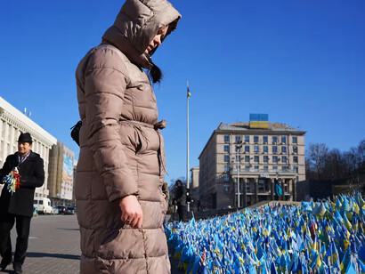 Una mujer busca la bandera que repreesenta a su hermano en el memorial para las víctimas de la guerra en Ucrania instalado con motivo de su primer aniversario