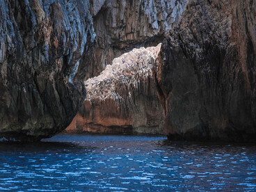 A vast volcanic cavern opening onto deep blue waters, representing the mysterious character of Milos’ coastline