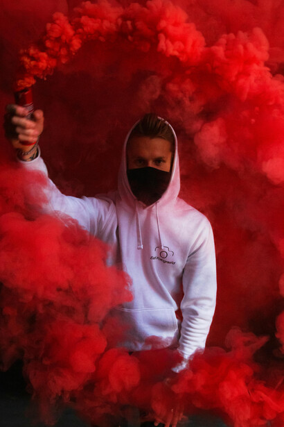 A masked man in a hoodie holds a smoke bomb during a scene in Tallinn, Harju County, Estonia