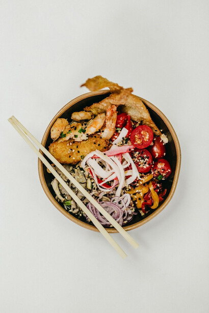 Capture the artistry of dining with a captivating image of chopsticks gracefully placed on a bowl filled with enticing food