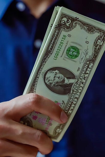 A man tightly clutching a stack of currency symbolizes the pervasive issue of corruption, highlighting the entwined relationship between individuals and illicit financial gains