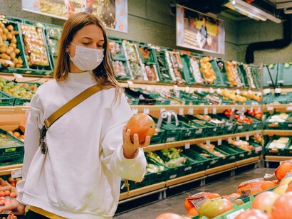 A woman food shopping at the supermarket and checking out some of the produce