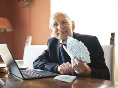 An elderly man with a stack of hundred-dollar bills showing his prowess in the silver economy