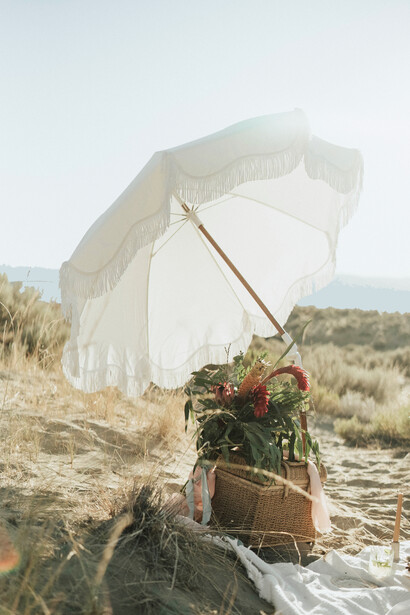 A white umbrella shades the picnic basket