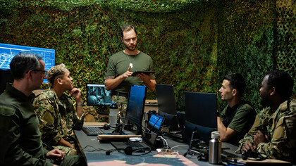 Young officer reviewing operational data on a tablet during a military strategy meeting