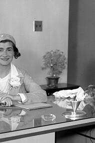 Coco Chanel sitting at a desk during a visit to Los Angeles, USA