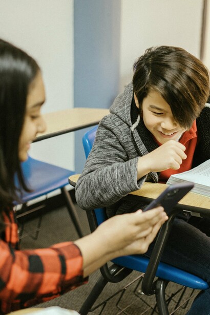 Students laugh over a text message in class