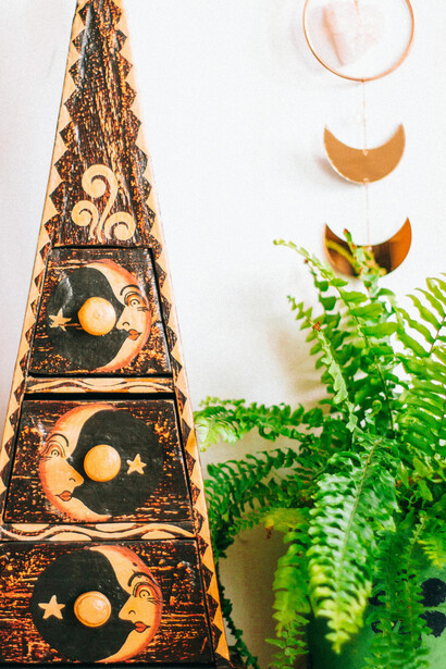 A unique pyramid-shaped wooden storage box with moon and star carvings