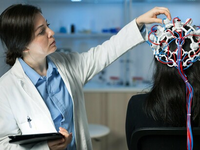 Mulher é examinada com o uso de um fone de ouvido de eletroencefalograma. Esses dispositivos são utilizados em diversas áreas, incluindo neurociência, monitoramento de saúde mental, e até mesmo para fins de desenvolvimento pessoal e bem-estar. Aplicativos e assistentes virtuais baseados nessa tecnologia estão ajudando milhões de pessoas a lidar com ansiedade, depressão e estresse