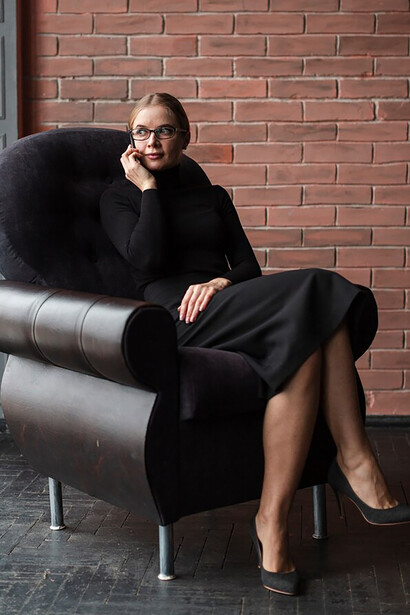 A modern woman sitting elegantly on a couch, exuding an old-money style