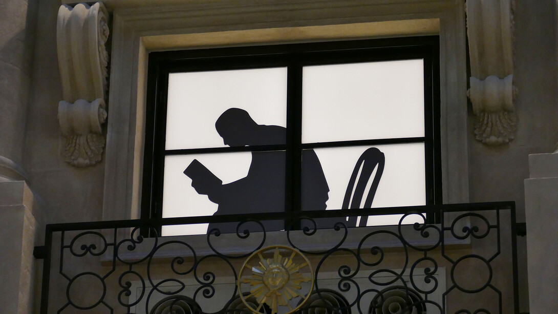 Ombra di un uomo alla finestra intento nella lettura di un libro