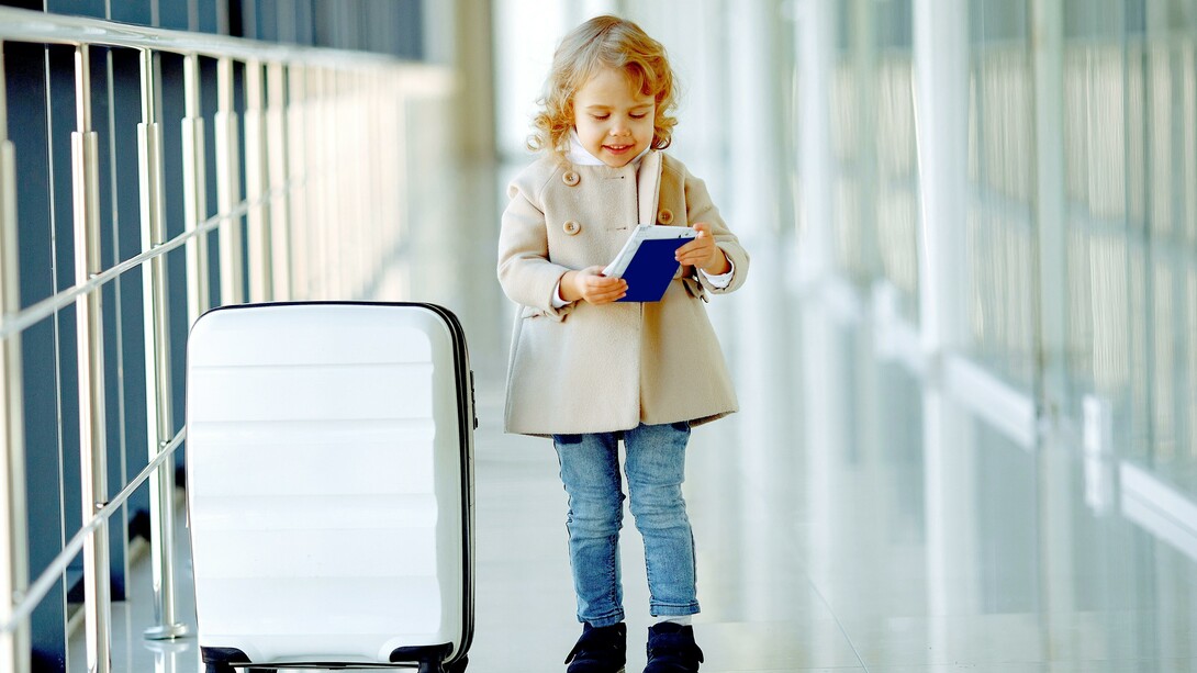 Menina feliz com mala e passaporte no corredor do aeroporto