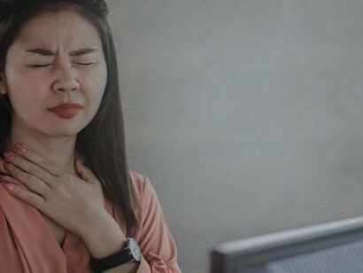 Discomfort in the throat could be caused by a case of acid reflux as demonstrated by this woman at her work
