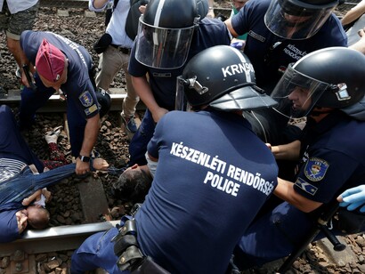 Policía e inmigrantes en una vía de ferrocarril