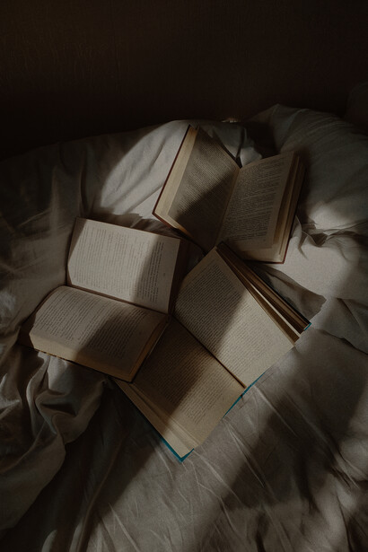 A bunch of old novels, laying open on an untidy bed