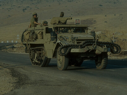Israeli armed halftrack drives down paved road during the Yom Kippur War on October 8, 1973, showcasing historic military maneuvers