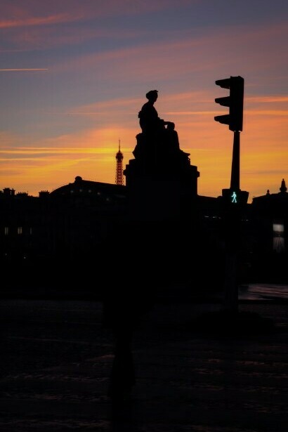 Dusk in Paris: pink clouds drift above a city street, where a lone streetlight casts a warm glow, France
