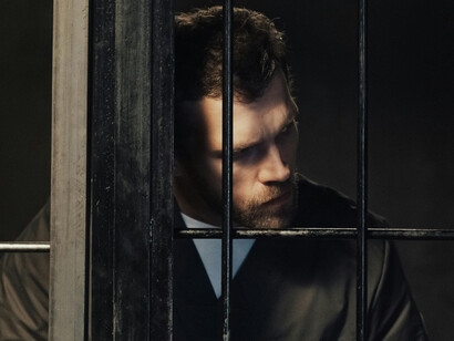 A man looks out from his cell behind bars
