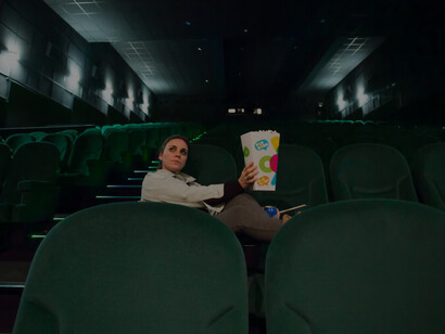 A girl with popcorn in a large cinema hall, embodying the moviegoing experience