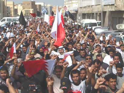 Protesters gather in a public square holding flags and signs demanding justice, political reform, and civil rights in Idlib, Idlib Governorate, Syria