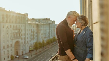 An elderly couple on a balcony, captured in a quiet moment as they share a kiss