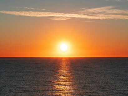 The sun rising over the the sea, painting the sky orange