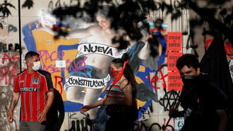 Manifestantes frente al grafiti que se volvió emblema del deseo de una nueva Constitución en Santiago, Chile